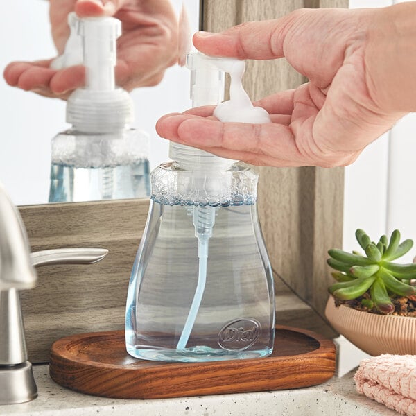 A person using a Dial Coconut Water foaming hand soap pump.