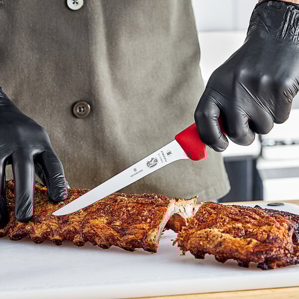 A person in black gloves using a Victorinox narrow boning knife to cut meat.
