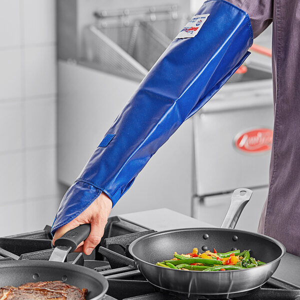 A person in a professional kitchen using a Tucker Safety blue nylon sleeve to cook over a stove.