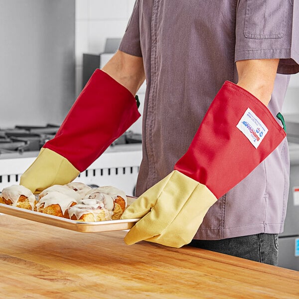 A man holding a tray of pastries wearing Tucker Safety Products oven gloves.