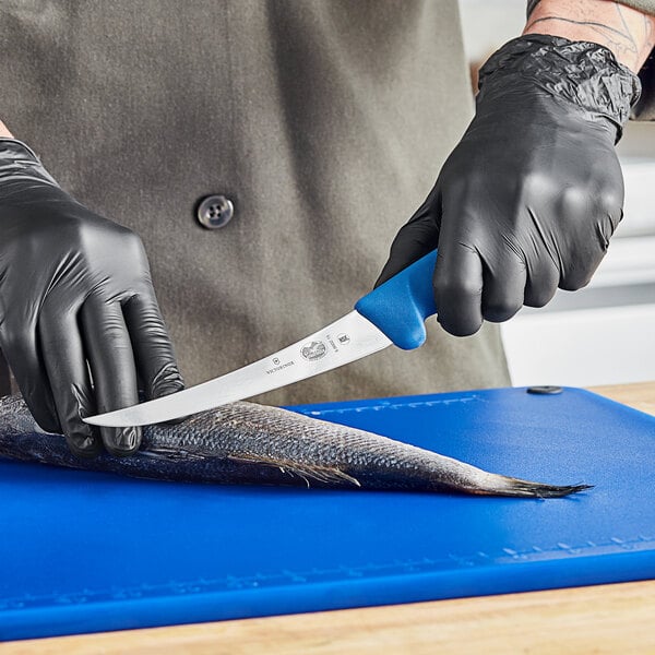 A person in black gloves using a Victorinox curved boning knife to cut a fish.