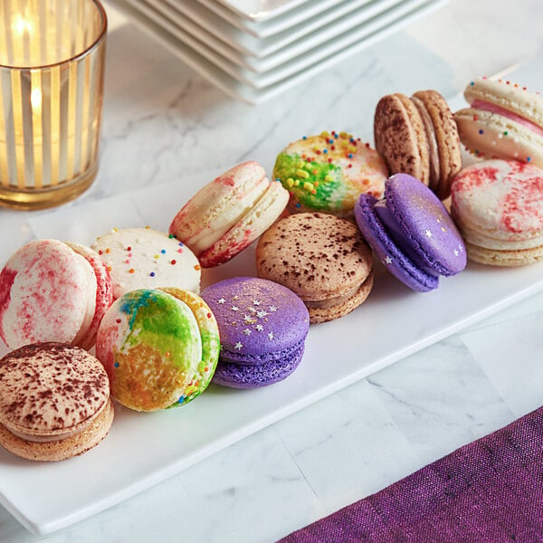 A white plate with colorful macarons on a table.