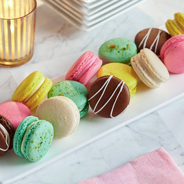 A white plate with a variety of colorful macarons on it.