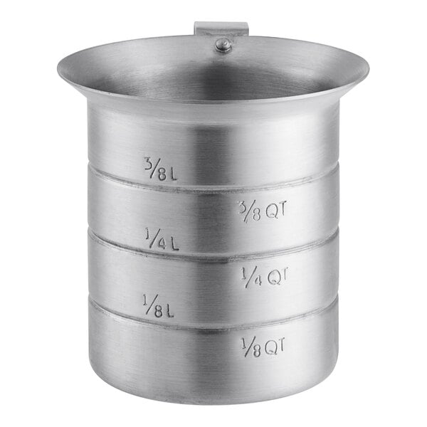 An aluminum measuring cup with a pour lip on a table with measuring cups.