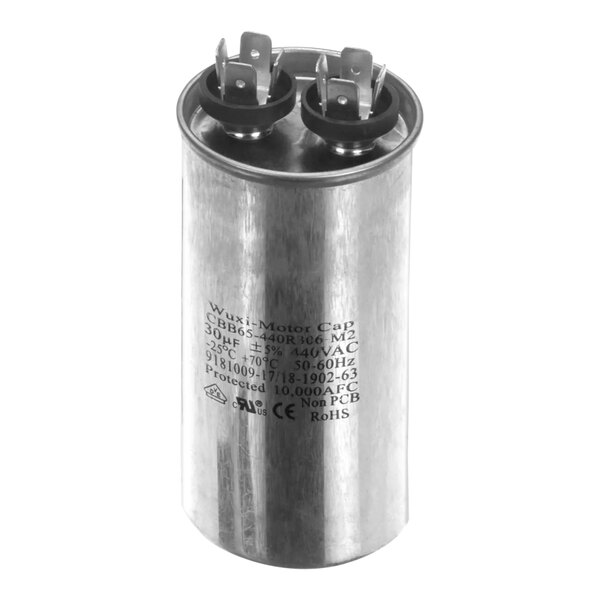 A close-up of a round metal Ice-O-Matic capacitor with black and white text.