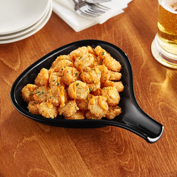 An Acopa black stoneware fry pan server with fried food on it.