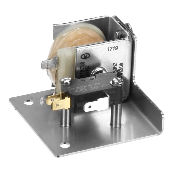 A white metal Fetco assembly solenoid latch box with a round object inside.