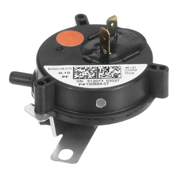 A black round pressure switch with orange and white markings and a white label.