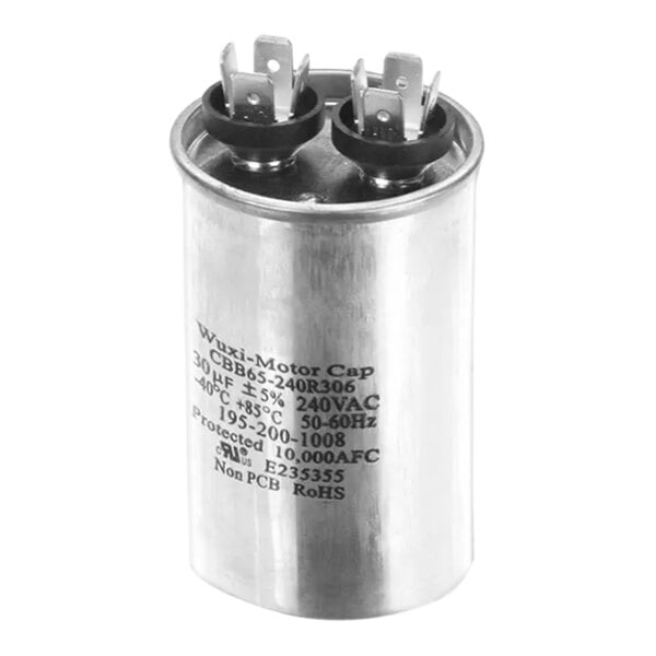 A close-up of a silver metal Scotsman capacitor with black text.