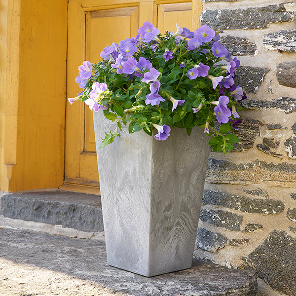 A Novelty Manufacturing Co. Ella tall square gray planter with purple flowers.