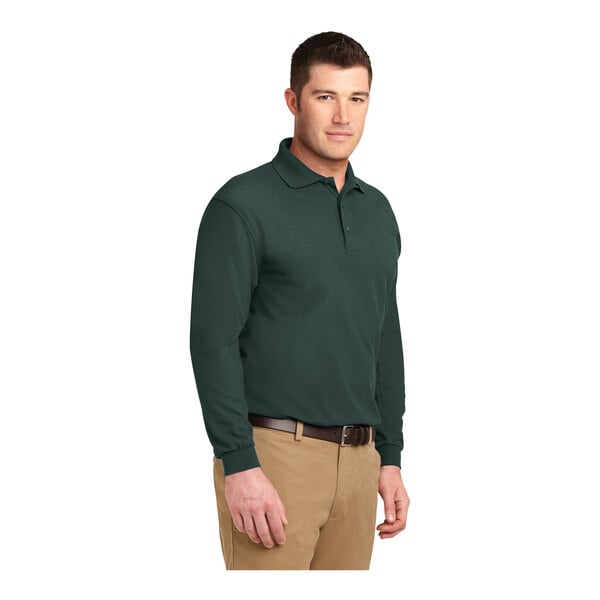 A close-up of a man wearing a dark green Port Authority® long sleeve polo shirt.