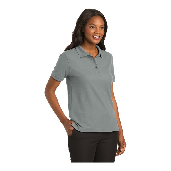A woman wearing a Port Authority cool gray short sleeve polo shirt.