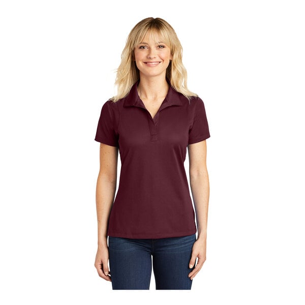 A woman wearing a maroon Sport-Tek short sleeve polo shirt.