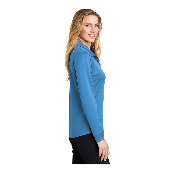 A woman wearing a Carolina blue Port Authority long sleeve polo shirt.