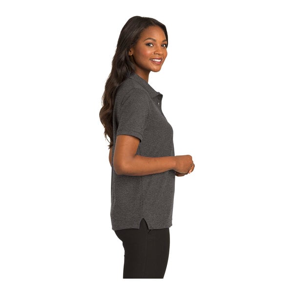 A woman wearing a Port Authority charcoal heather grey silk touch polo shirt with a buttoned collar.