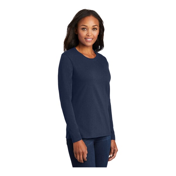 A woman wearing a Port & Company navy long sleeve t-shirt.
