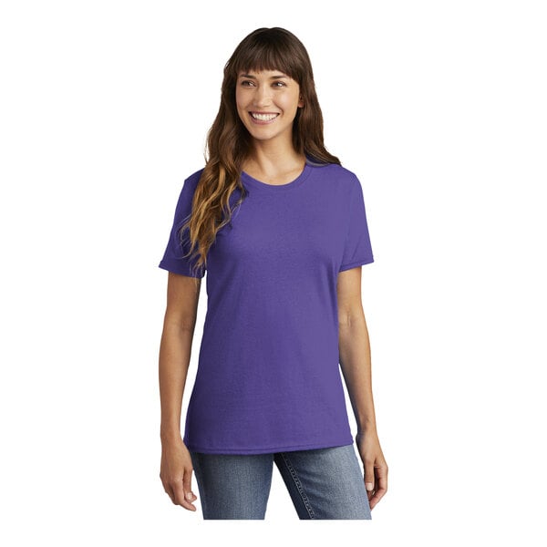 A woman wearing a purple Port & Company short sleeve t-shirt.