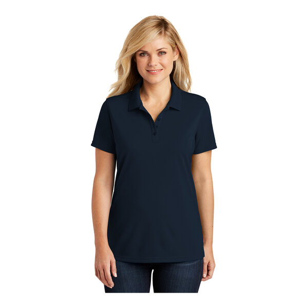 A woman wearing a navy blue Port Authority Dry Zone short sleeve polo shirt.