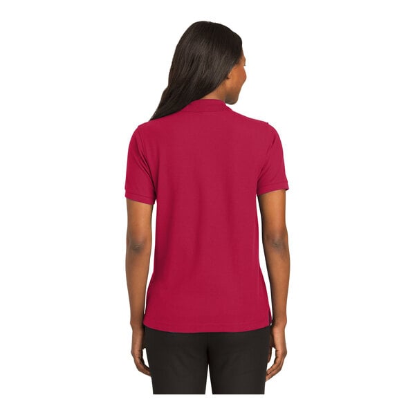 A woman wearing a red Port Authority silk touch polo shirt.
