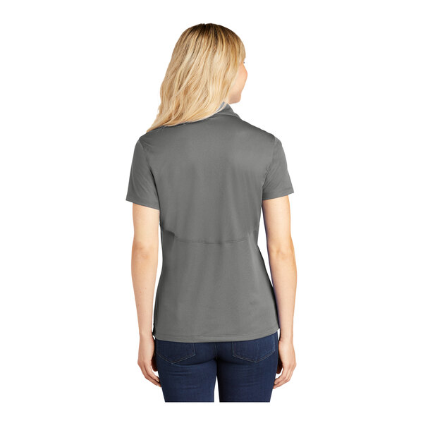 A woman wearing a grey Sport-Tek polo shirt.