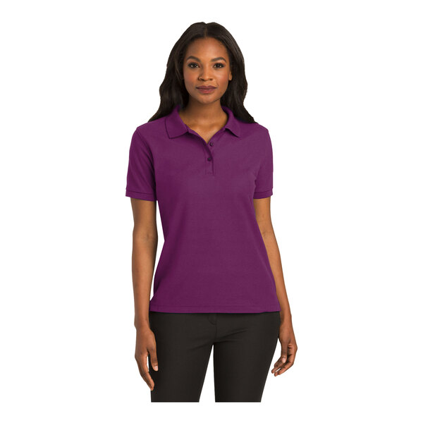 A woman wearing a Port Authority deep berry silk touch polo shirt.