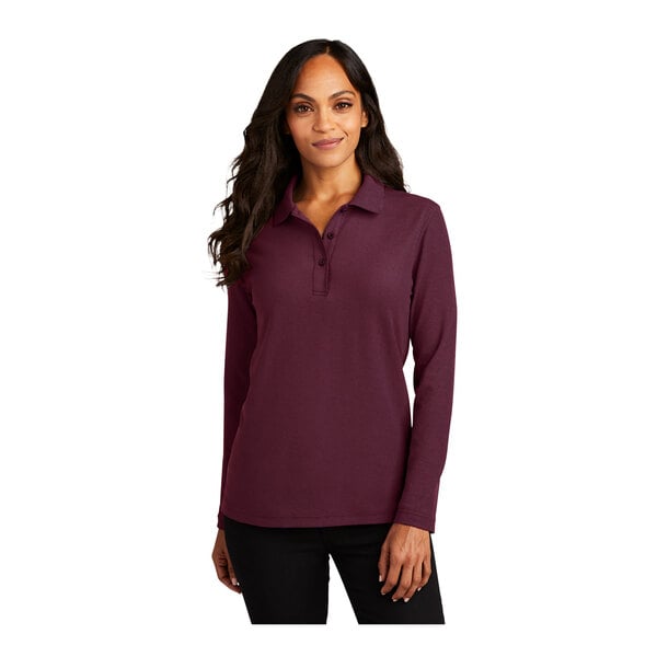 A woman wearing a burgundy Port Authority long sleeve polo shirt.