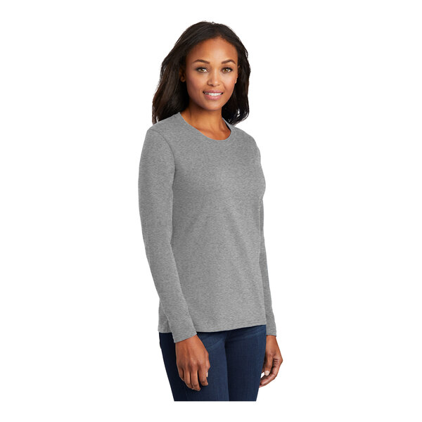 A woman wearing a Port & Company athletic heather long sleeve t-shirt.