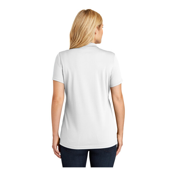 A woman wearing a white Port Authority Dry Zone polo shirt.