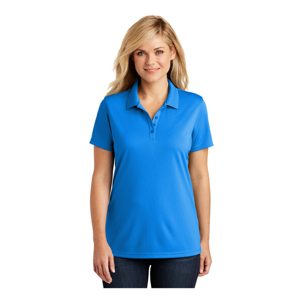 A woman wearing a Port Authority women's blue short sleeve polo shirt.