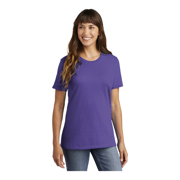 A woman wearing a purple Port & Company t-shirt.