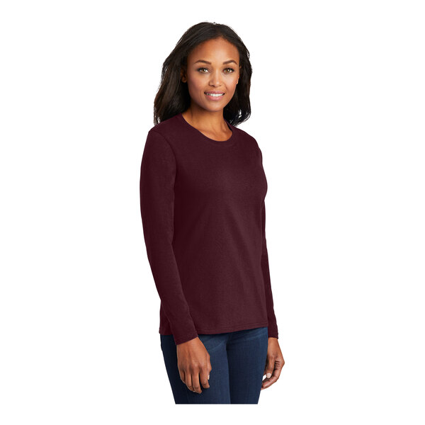 A woman wearing a maroon Port & Company long sleeve t-shirt.