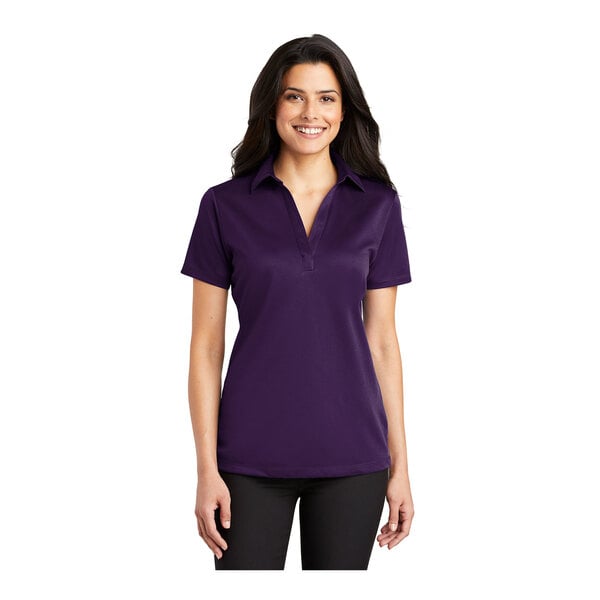 A woman wearing a Port Authority bright purple short sleeve polo shirt.