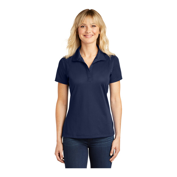 A woman wearing a navy blue Sport-Tek short sleeve polo shirt with a collar.