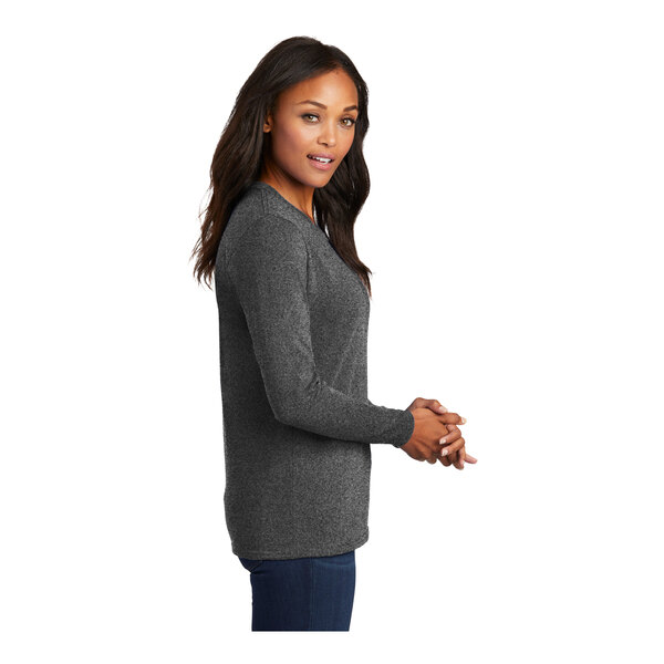 A woman wearing a dark heather grey Port & Company long-sleeve t-shirt.