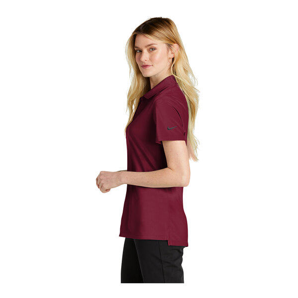 A woman wearing a maroon Nike Team Red polo shirt.