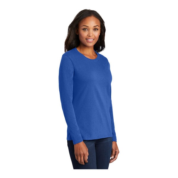 A woman wearing a Port & Company royal blue long sleeve t-shirt.