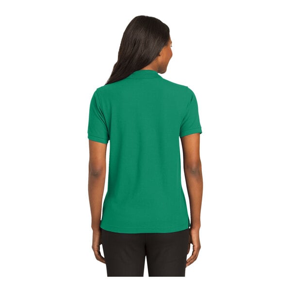 A woman wearing a Port Authority Kelly Green polo shirt.