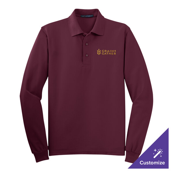 A Port Authority long sleeved maroon polo shirt on a counter with gold embroidery.