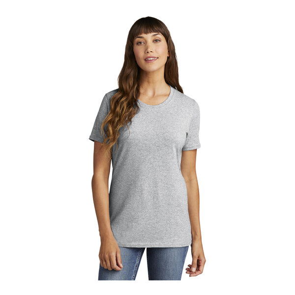 A woman wearing a grey Port & Company short sleeve t-shirt with a crew neck.