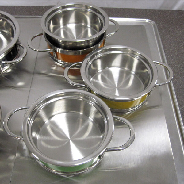 A stainless steel Bon Chef insert pan in a tray with several classic country French pots.