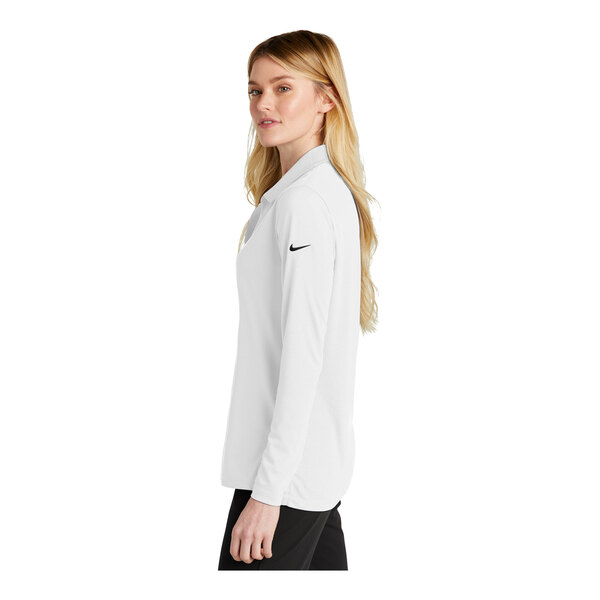 A woman wearing a white Nike long sleeve polo with black trim.