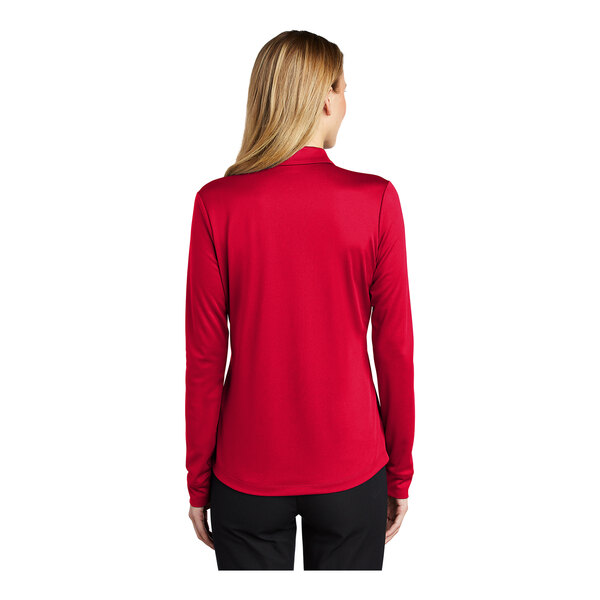 A woman wearing a Port Authority red long sleeve polo shirt.