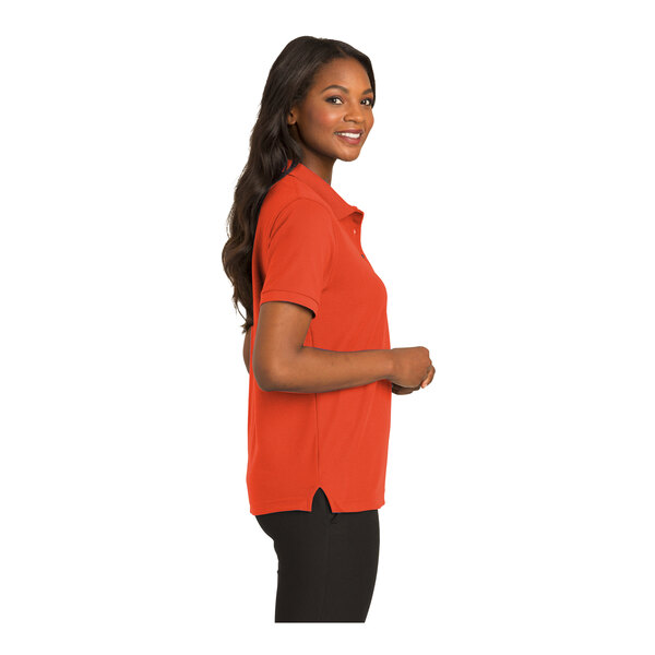 A woman wearing an extra large orange Port Authority polo shirt.