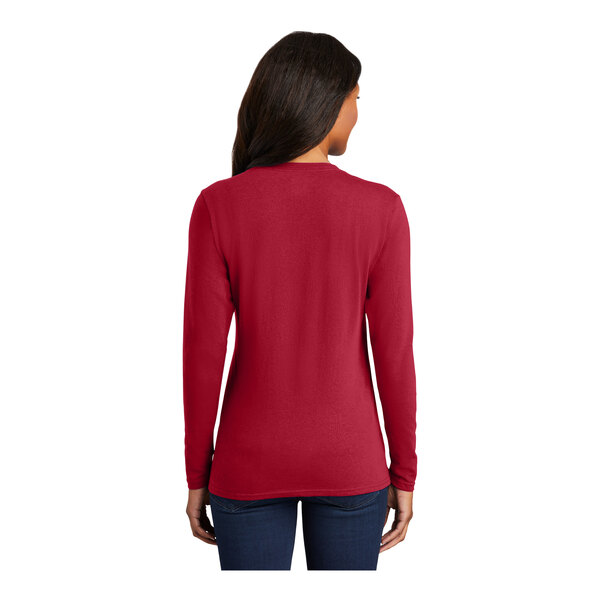 A woman wearing a Port & Company red long sleeve shirt.