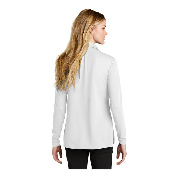 A woman wearing a white Nike long sleeve polo.