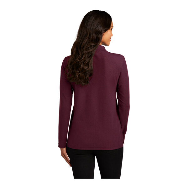 A woman with long brown hair wearing a Port Authority burgundy long sleeve polo.