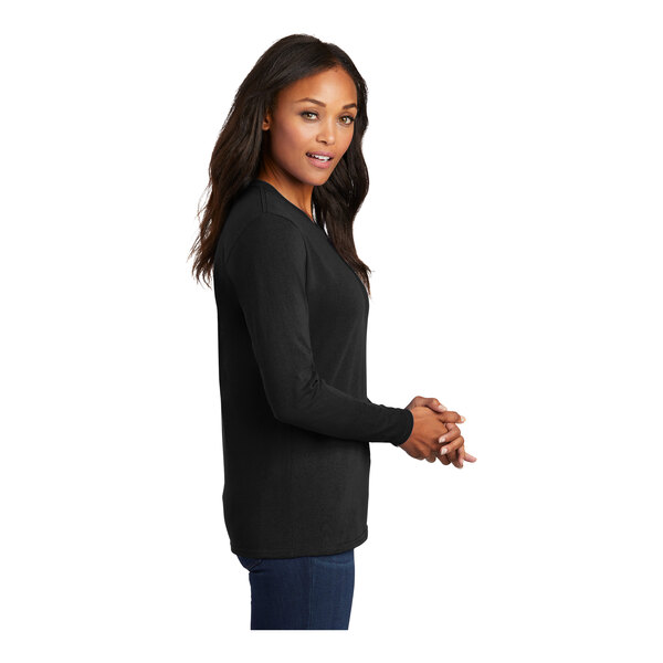 A woman wearing a black Port & Company long sleeve T-shirt.