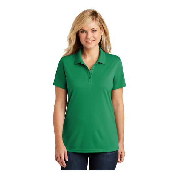 A woman wearing a bright kelly green Port Authority polo shirt with short sleeves.