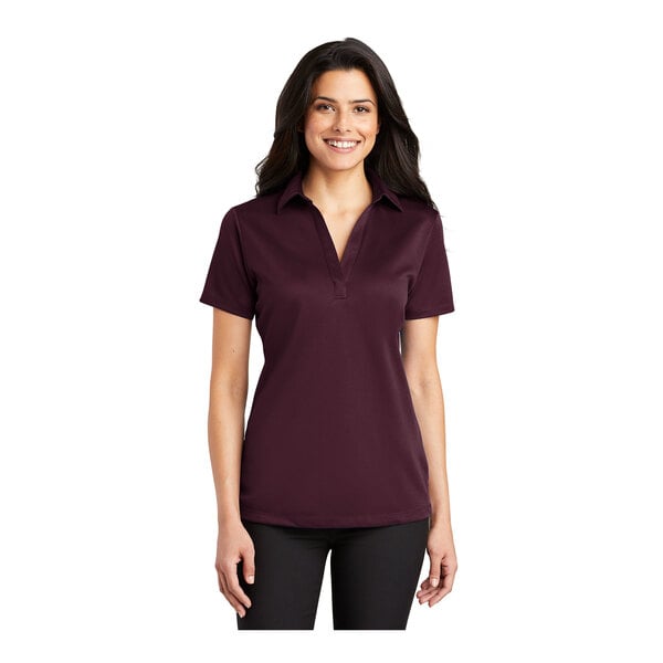A woman wearing a maroon Port Authority silk touch polo shirt.