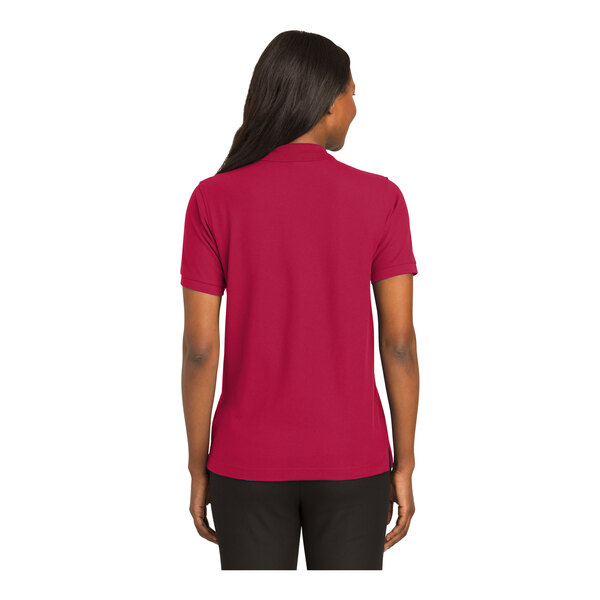 A woman wearing a red Port Authority polo shirt.